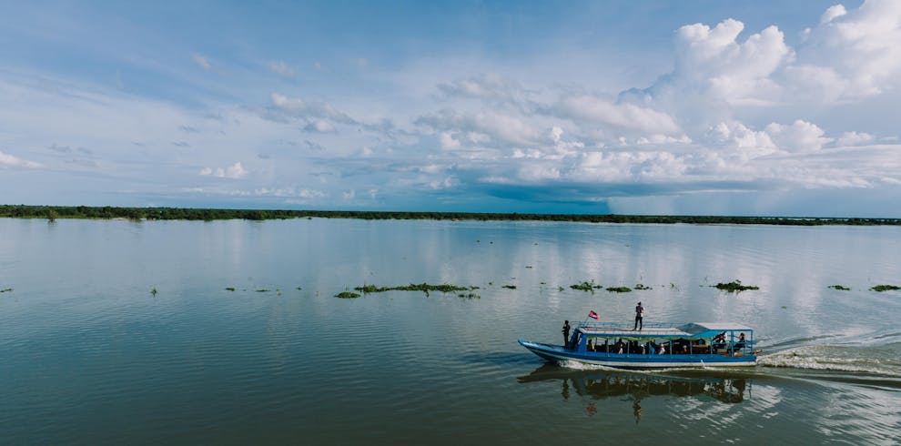 A serene view of a boat on Tonle Sap Lake under a vast sky in Cambodia.