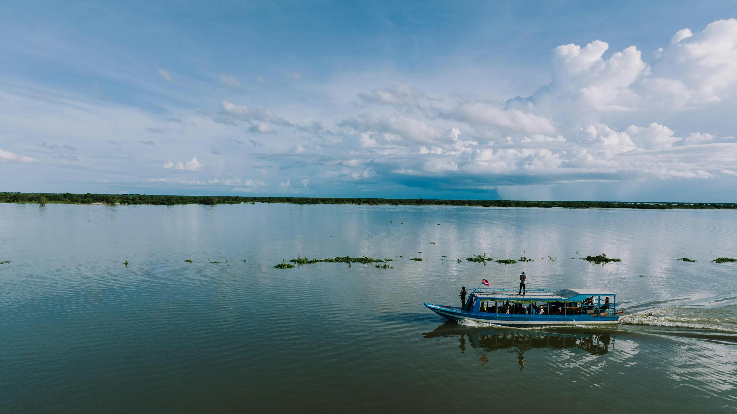A serene view of a boat on Tonle Sap Lake under a vast sky in Cambodia.