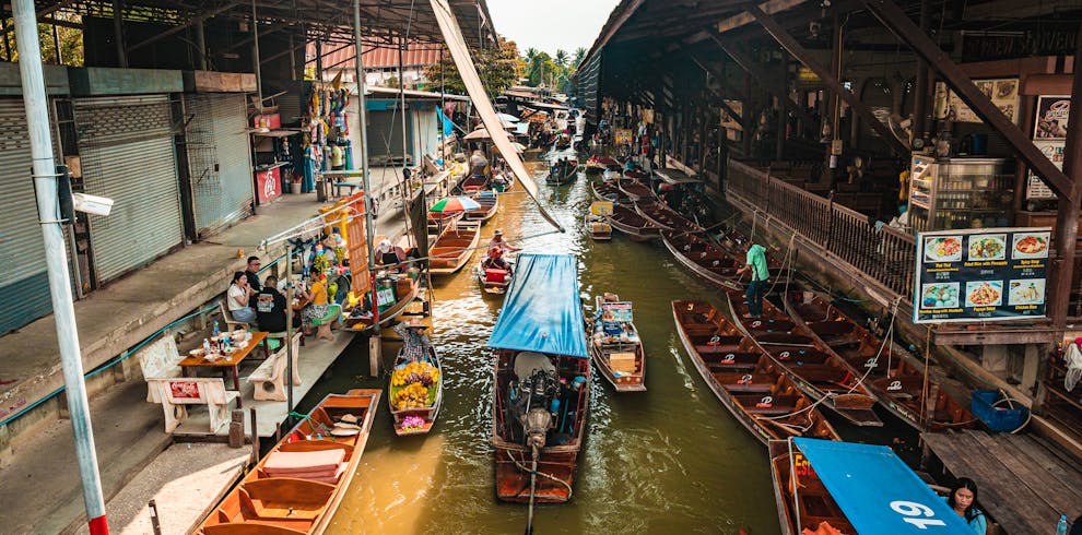 Bustling floating market in Bangkok with colorful boats and traditional vendors along the canal.