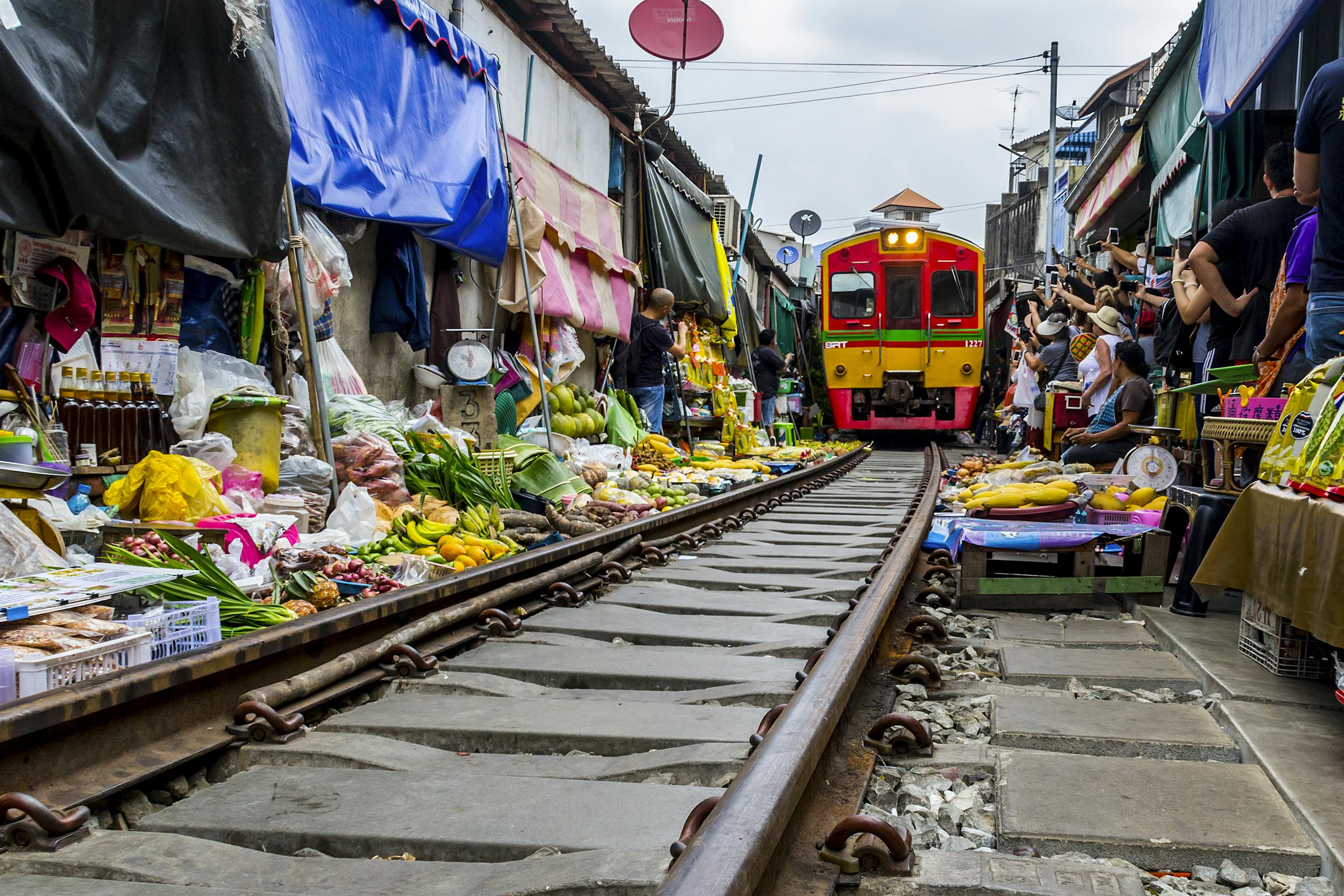 Capture the excitement of Mae Klong Market in Thailand with a train passing through vibrant stalls filled with fresh produce.