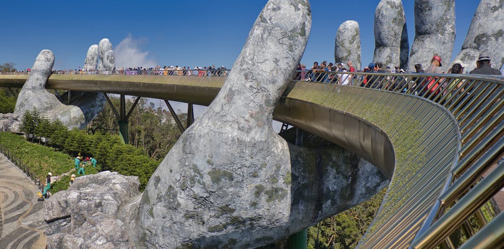 The iconic Golden Bridge with giant hand sculptures at Ba Na Hills, Vietnam, under a clear blue sky.