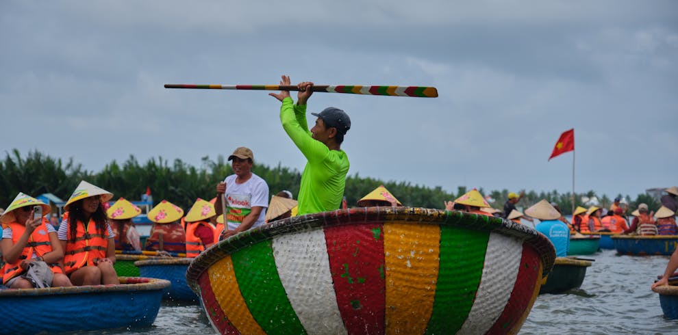Tourists enjoy a spinning basket boat experience in Hội An, Vietnam, showcasing local culture.